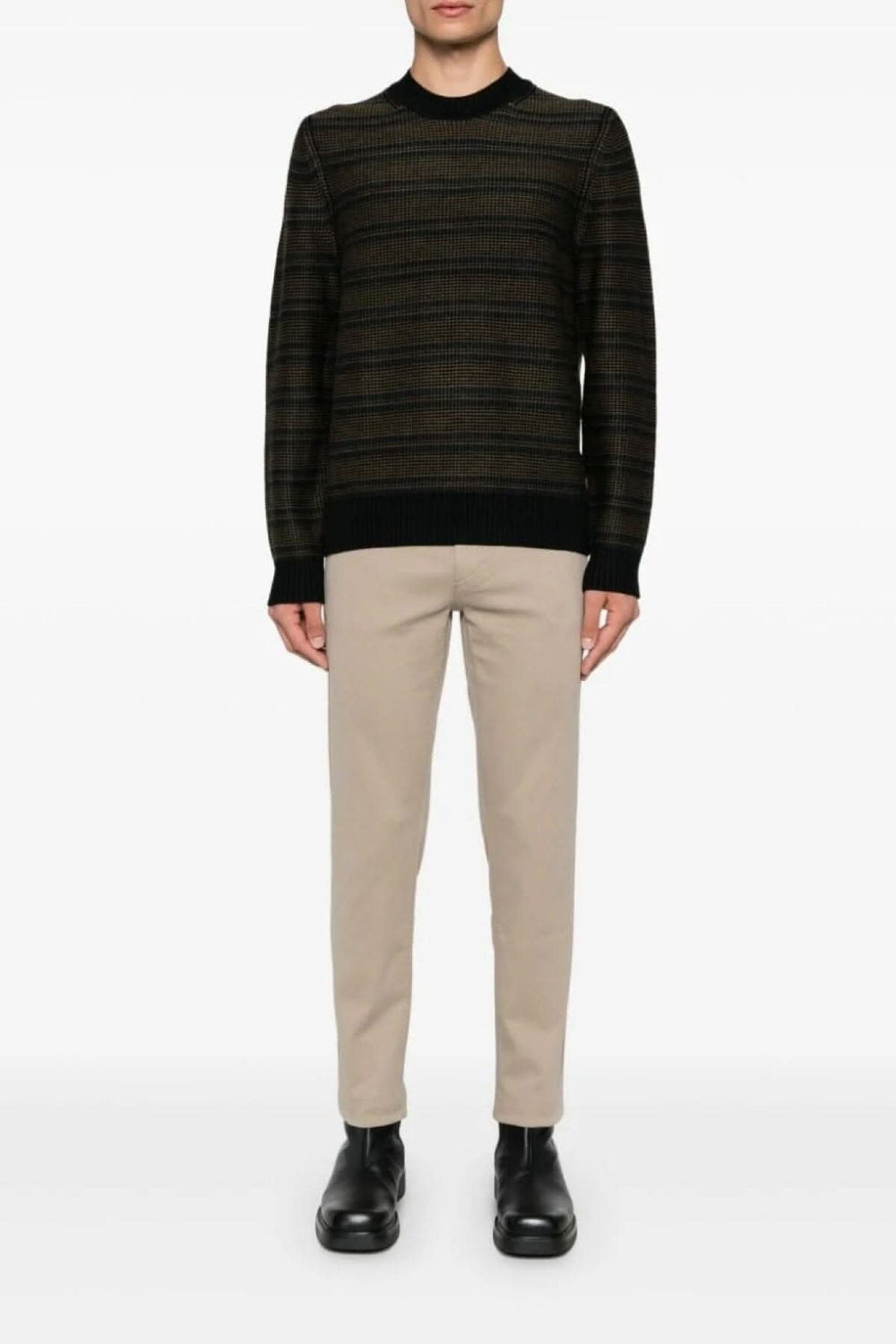 Pull à col rond avec rayures contrastées, porté avec un pantalon beige et des chaussures noires.