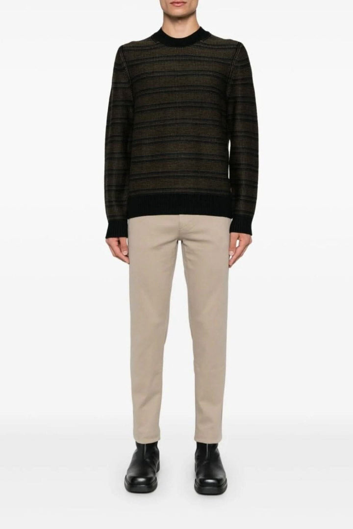 Pull à col rond avec rayures contrastées, porté avec un pantalon beige et des chaussures noires.
