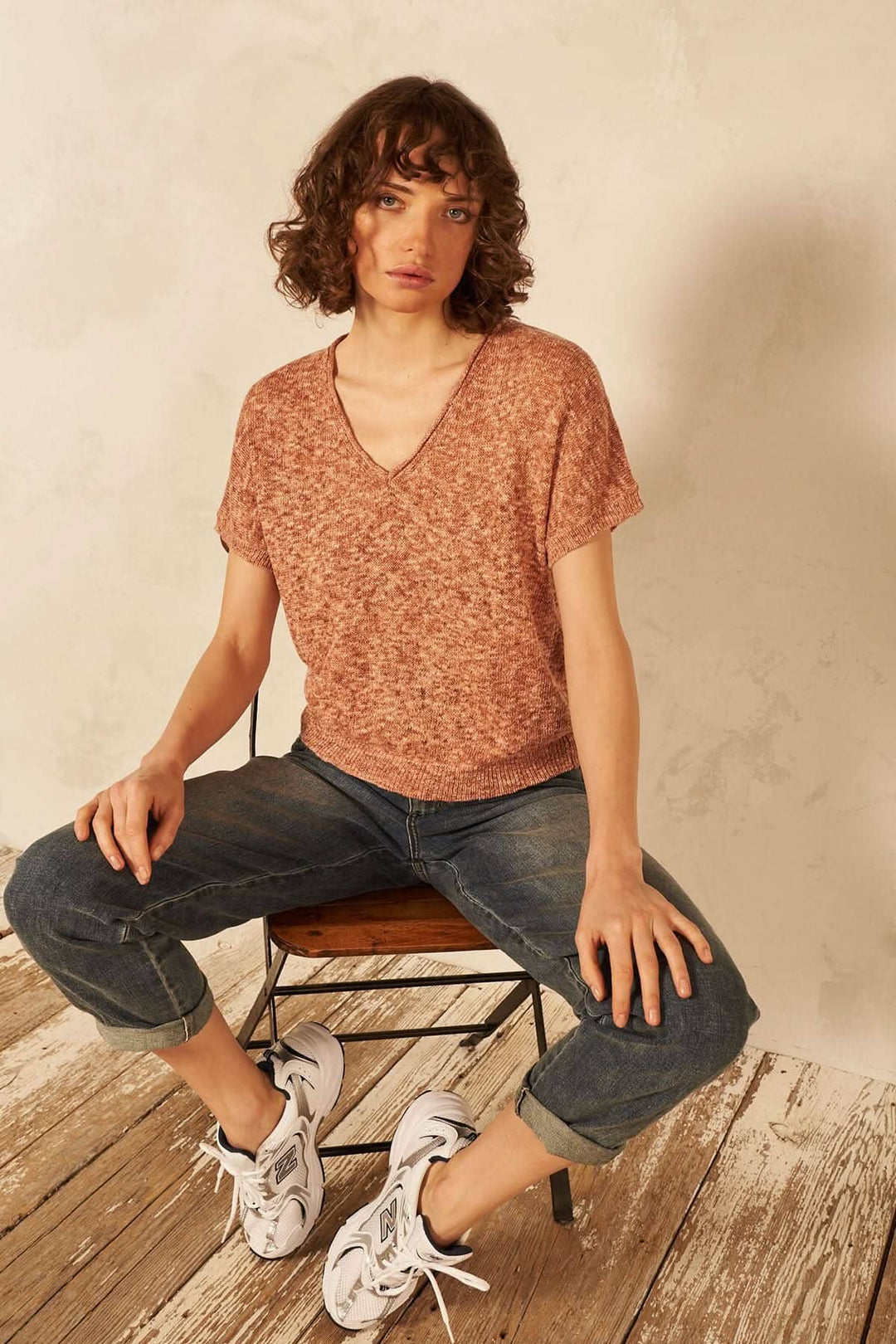 Chandail tendance à manches courtes, encolure en V, porté avec un style décontracté, sur fond neutre.