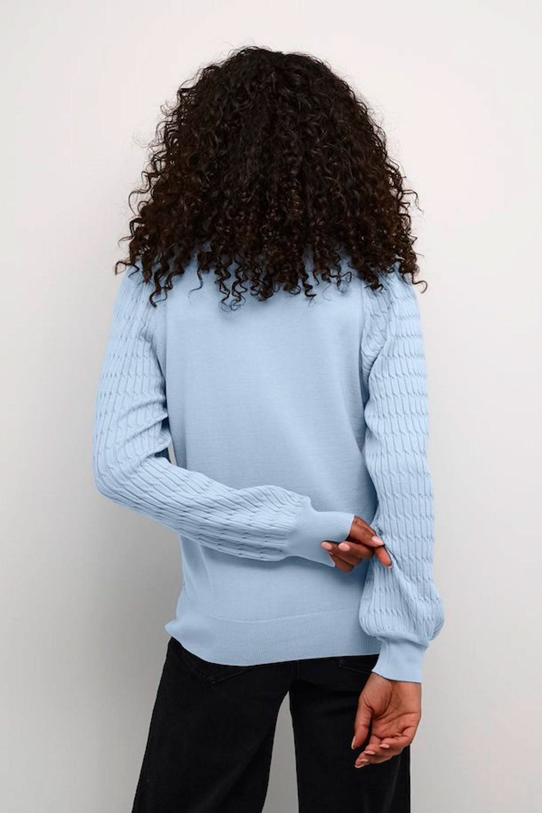 Chandail en tricot bleu clair avec motifs sur les manches, vue de dos, style décontracté.