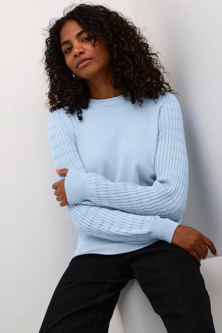 Chandail bleu avec manches à motifs de tricot, offrant confort et style décontracté.