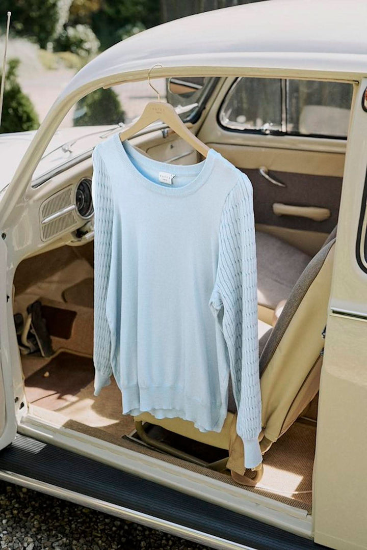 Chandail bleu clair avec motifs de tricot suspendu à l'intérieur d'une voiture vintage.
