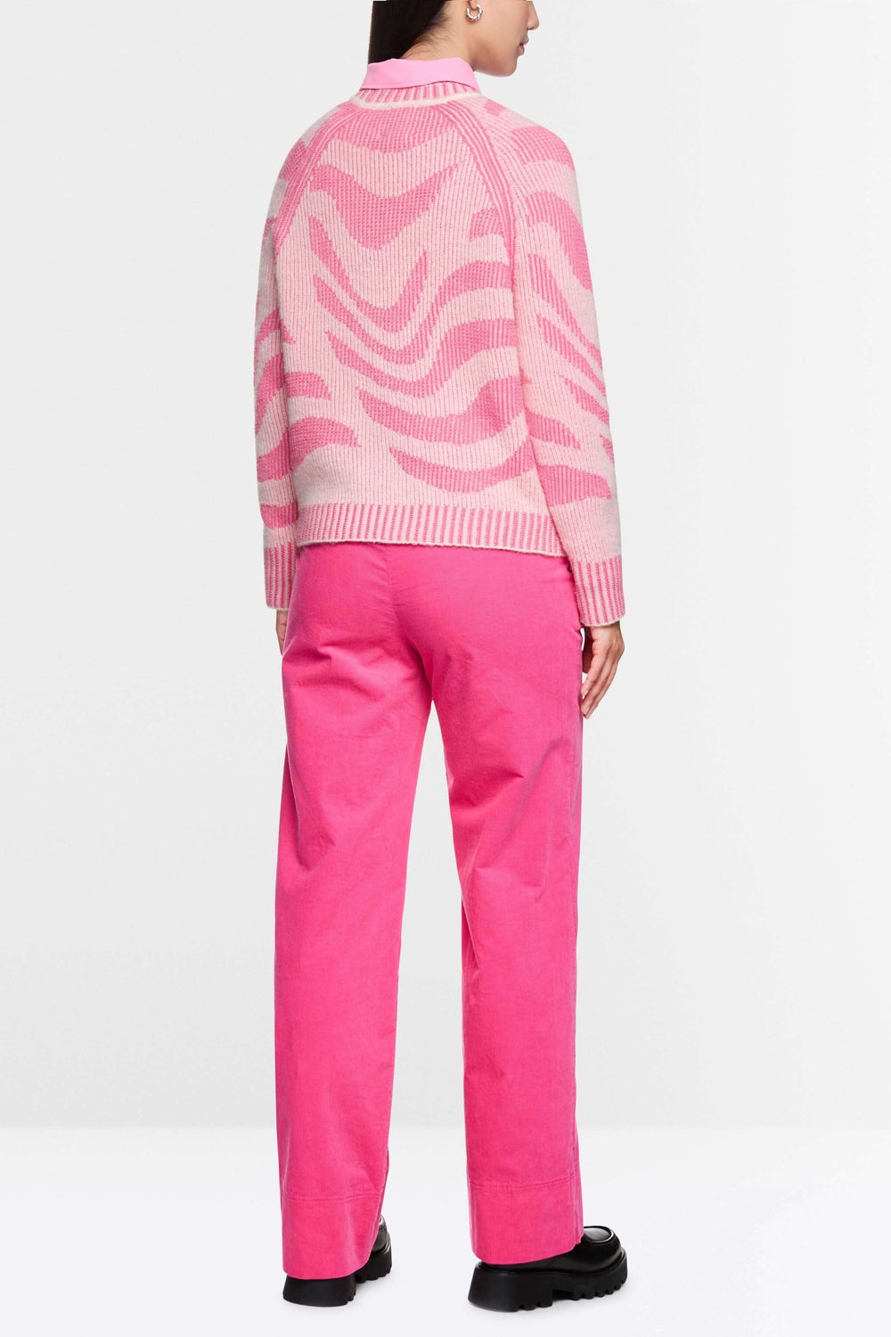 Personne portant un chandail motif dégradé rose avec manches longues et pantalon rose, vue de dos, style moderne et audacieux.