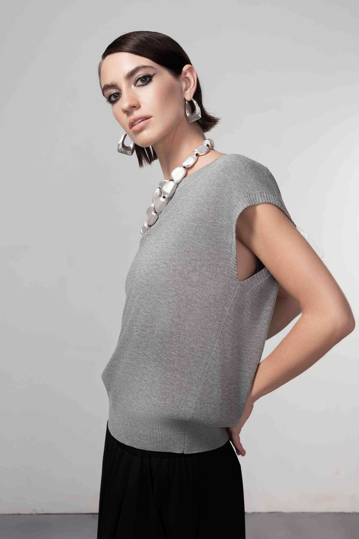 Femme portant un chandail ouverture au dos, sans manches avec maille fine, style contemporain et silhouette épurée.