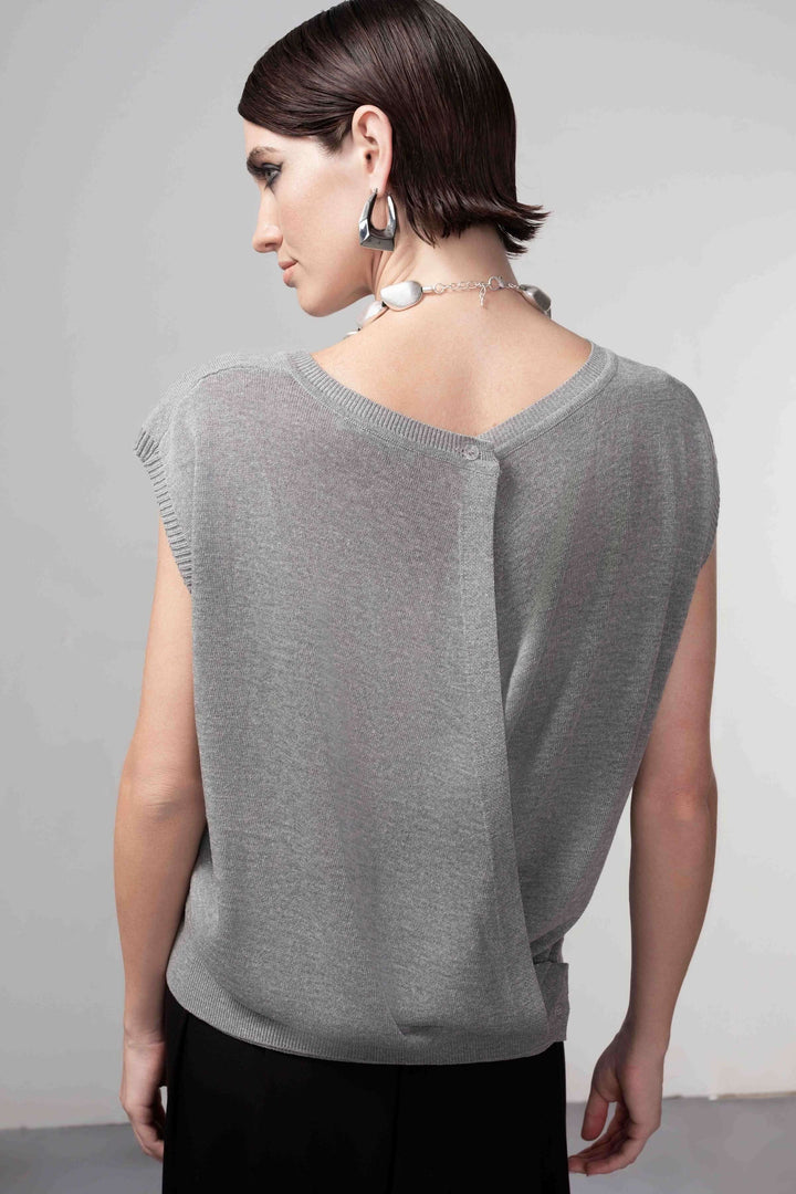 Femme portant un chandail ouverture au dos, maille fine, coupe droite, style contemporain et épuré, couleur grise.