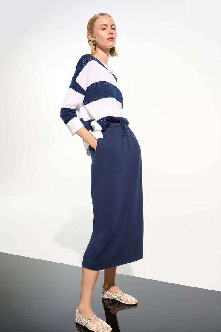 Femme portant un chandail rayé ajouré avec jupe droite, look décontracté et élégant, idéal pour la mi-saison.