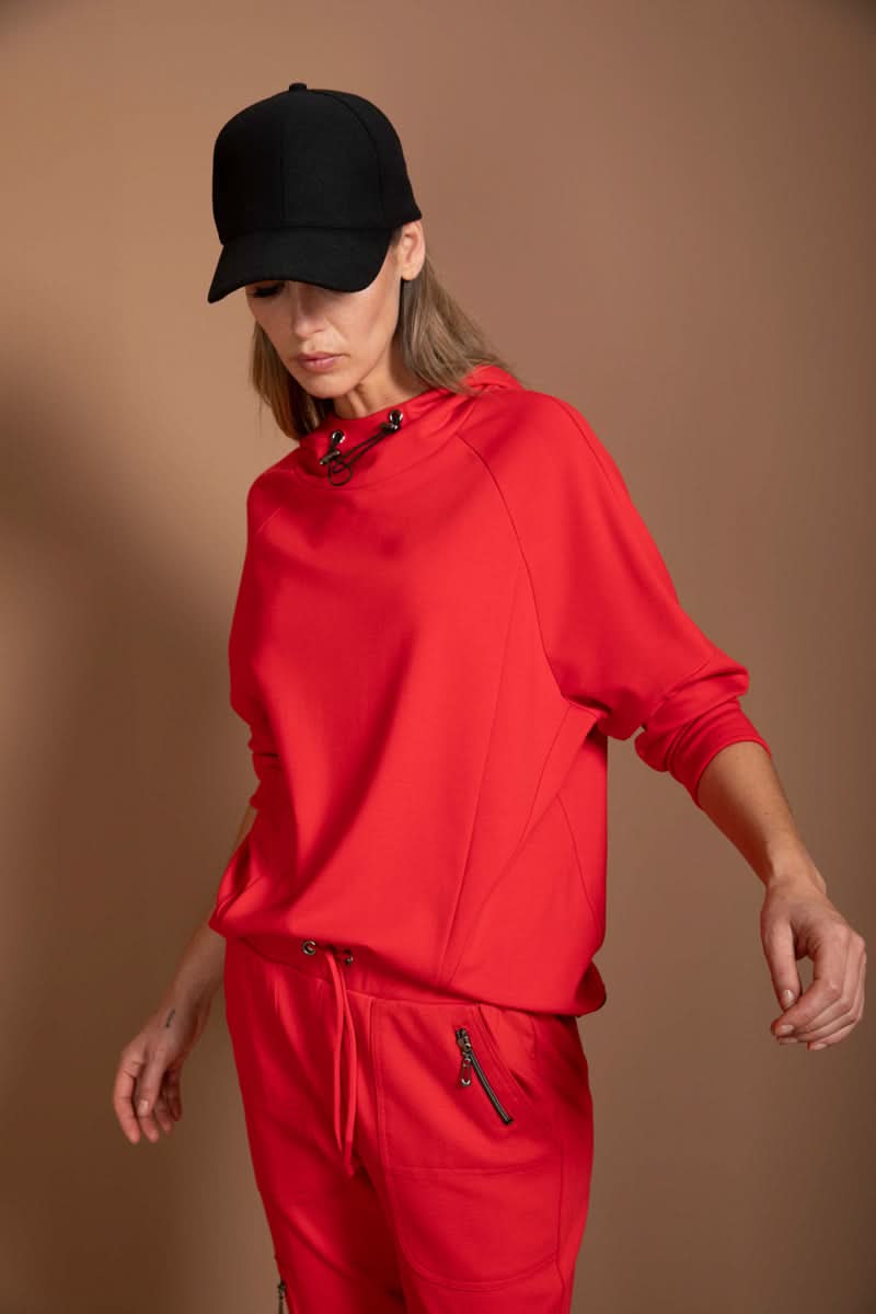 Chandail structuré rouge avec col montant ajustable, style athleisure moderne pour un look dynamique.