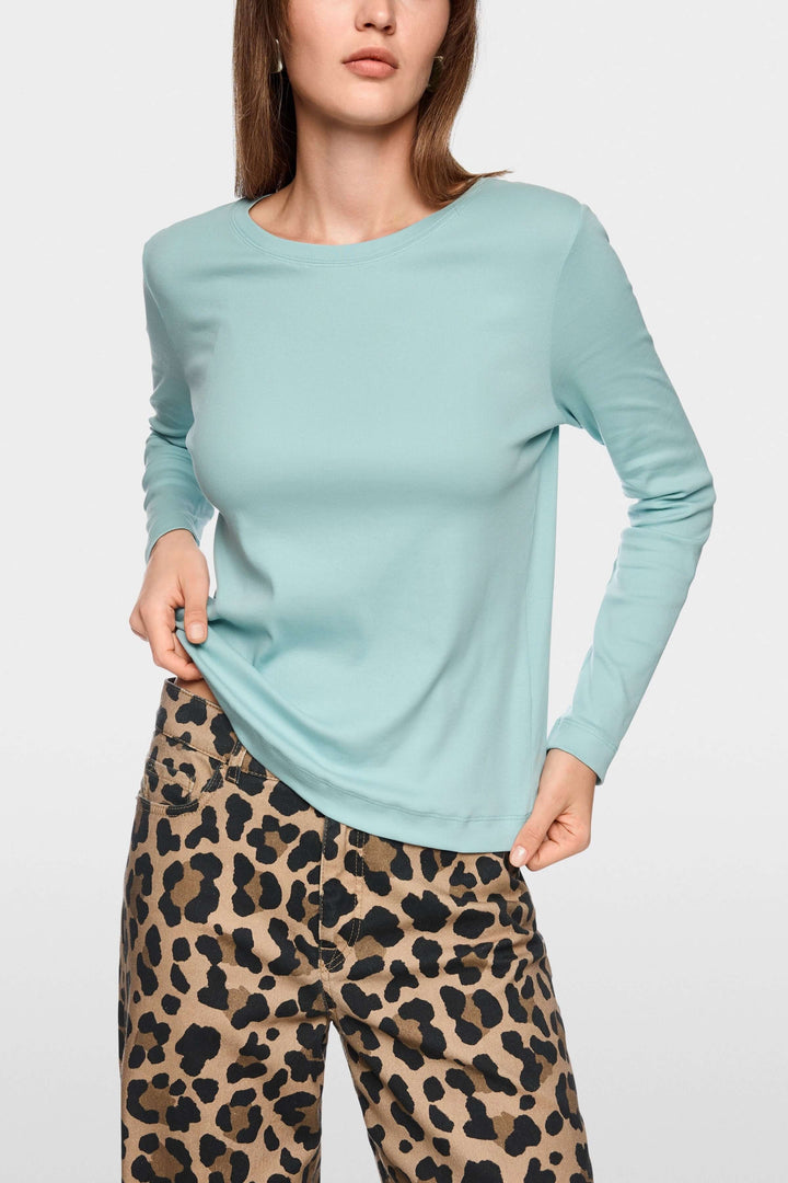 Femme portant un chandail unie à manches longues, coupe ajustée, avec un pantalon imprimé léopard, style chic et minimaliste.