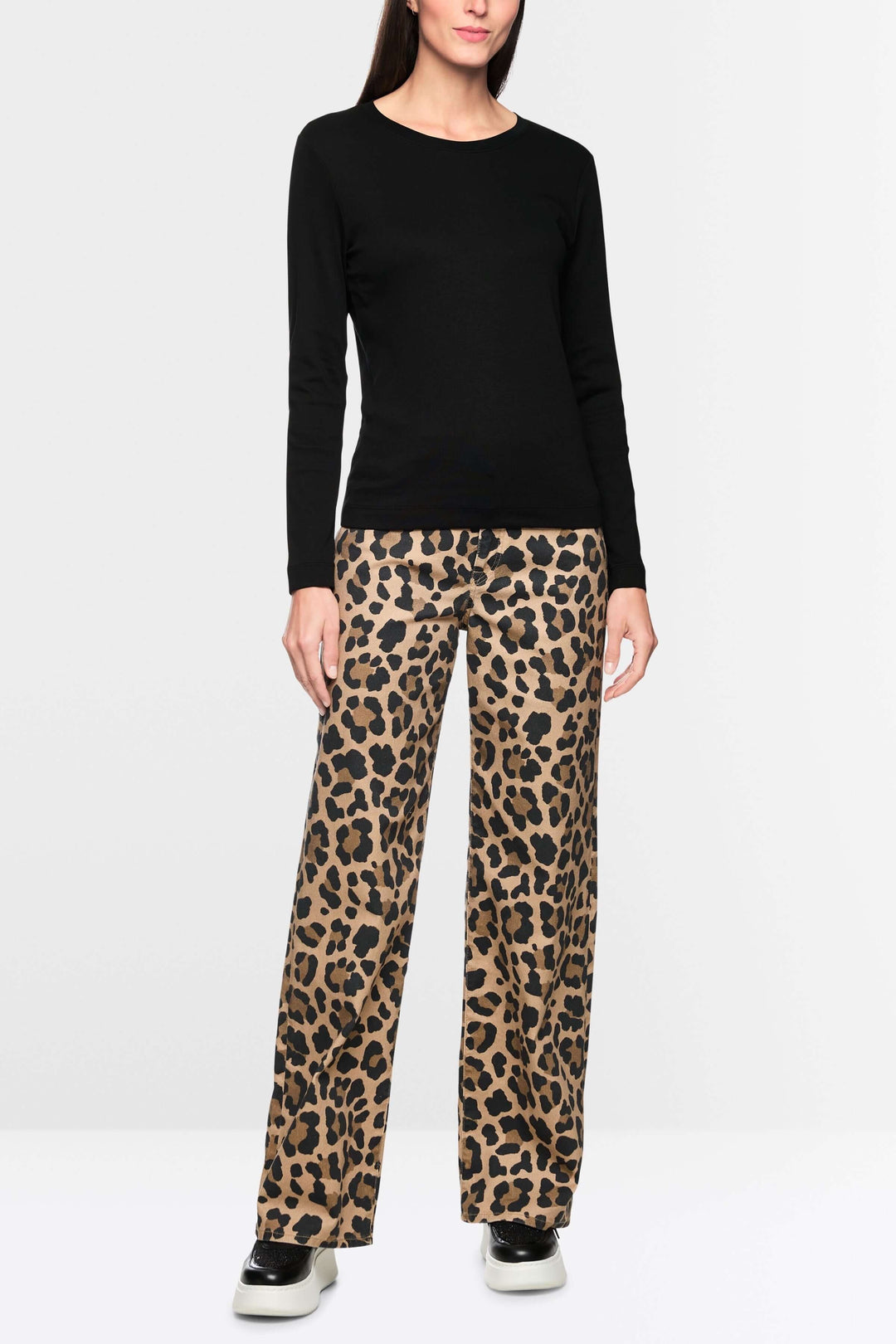 Femme portant un chandail unie à manches longues noir avec un pantalon léopard, style chic et décontracté.