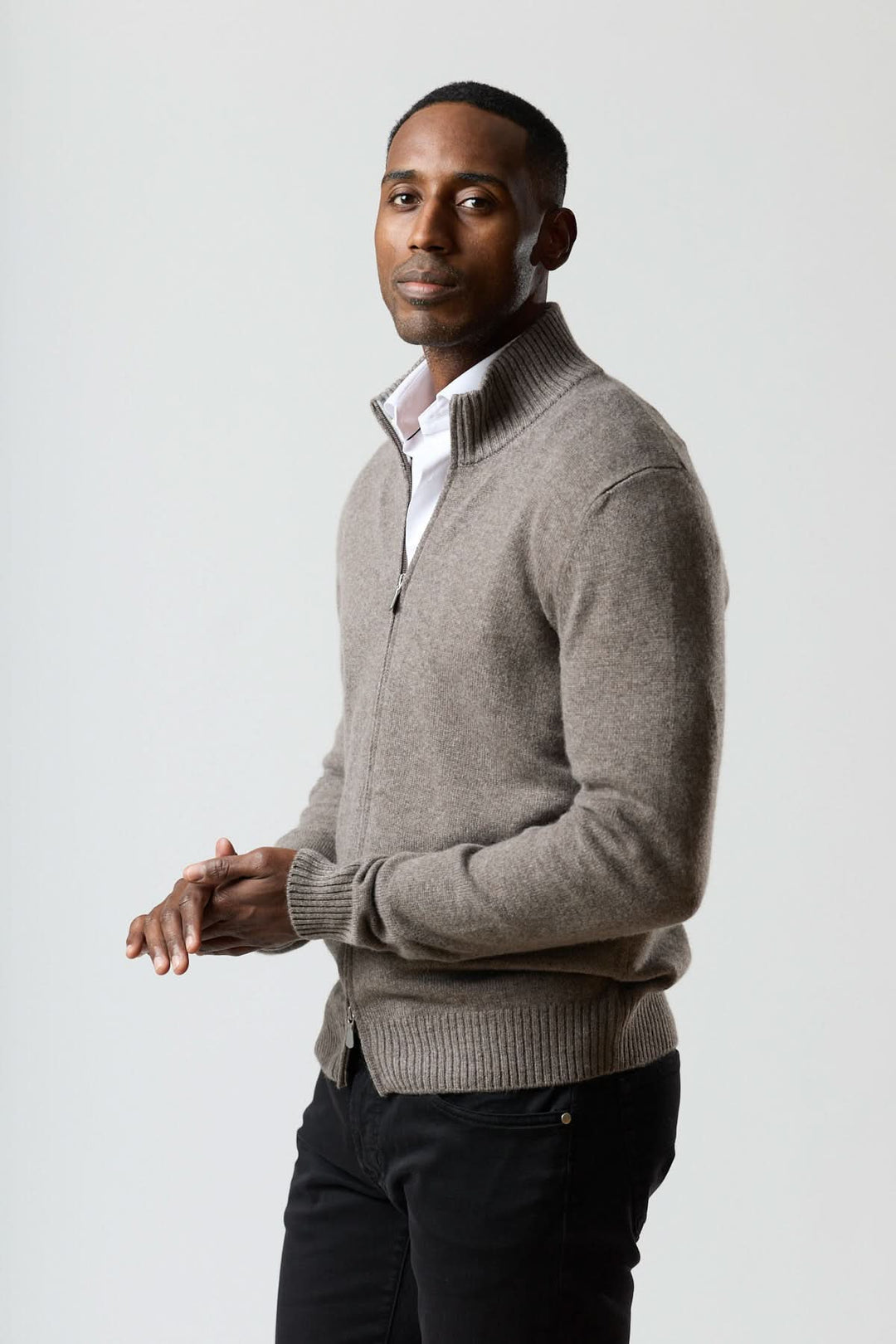 Homme portant un chandail zippé col montant en maille douce avec fermeture éclair, sur une chemise blanche, look propre et masculin.