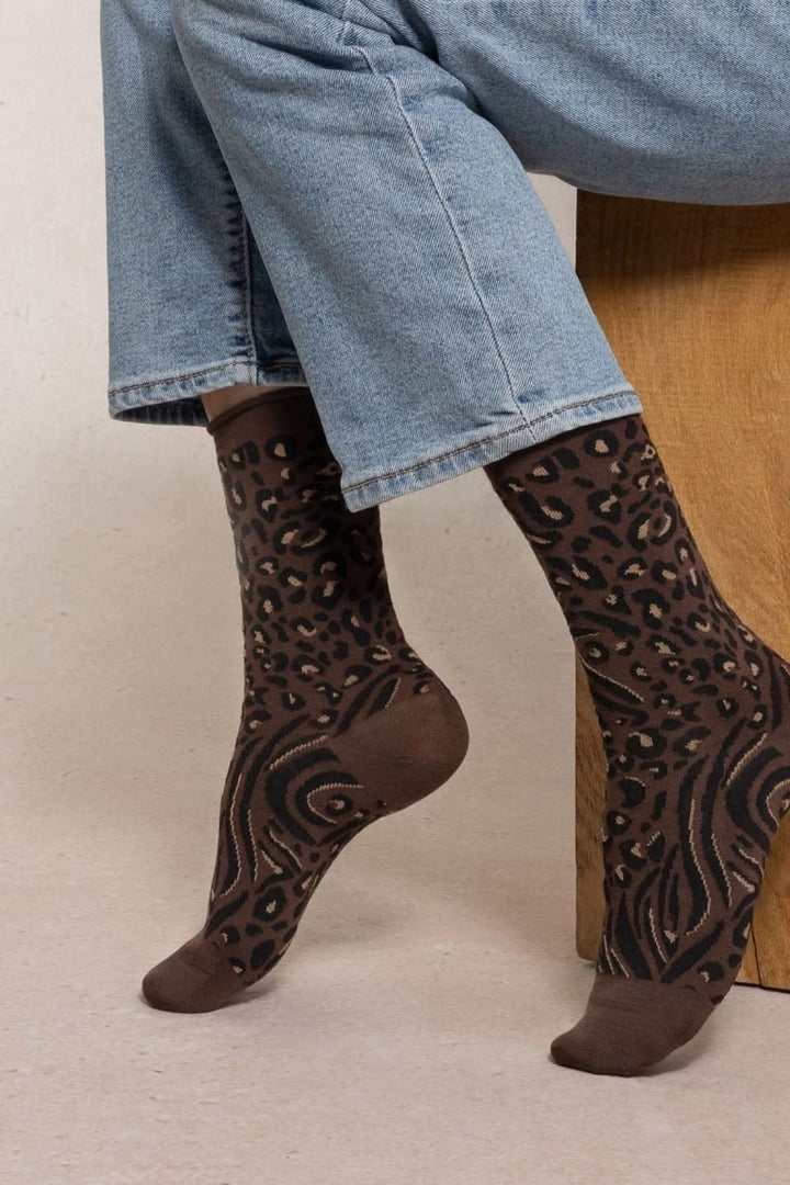 Chaussettes en maille à motif animalier portées avec un jean retroussé, en laine et coton pour chaleur et confort.