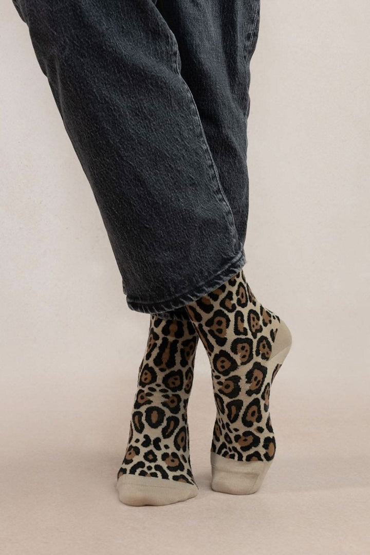 Chaussettes léopard confortables avec motif intégral, portées avec un pantalon noir.