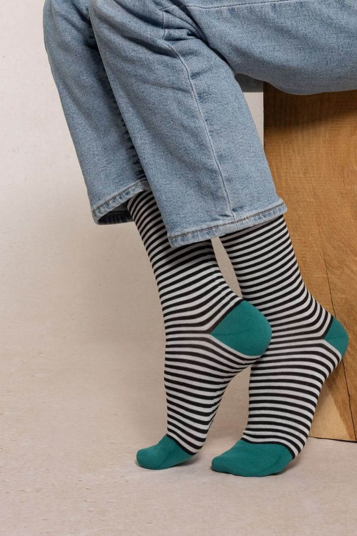Chaussettes à rayures fines confortables avec talon vert, portées avec un jean. Idéales pour une touche élégante et moderne.