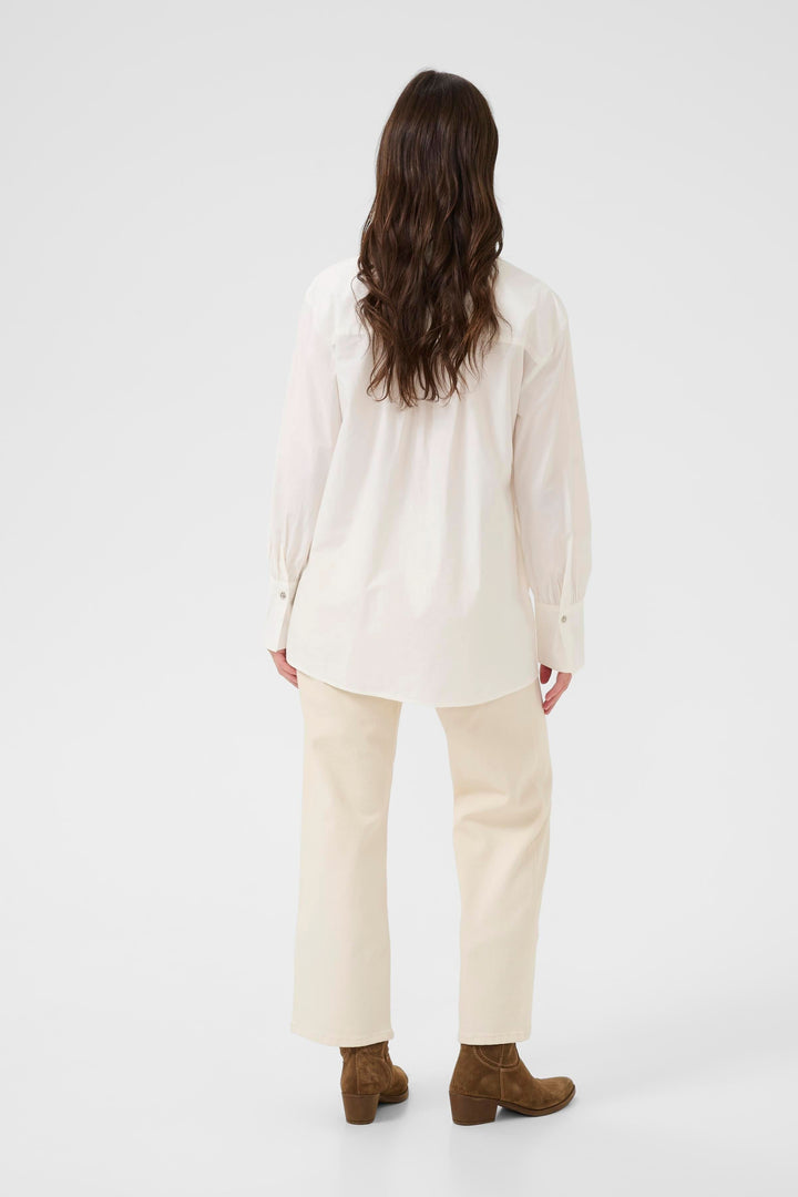 Vue arrière de la Chemise Alison blanche, élégante et fluide, associée à un pantalon beige et des bottines marron.