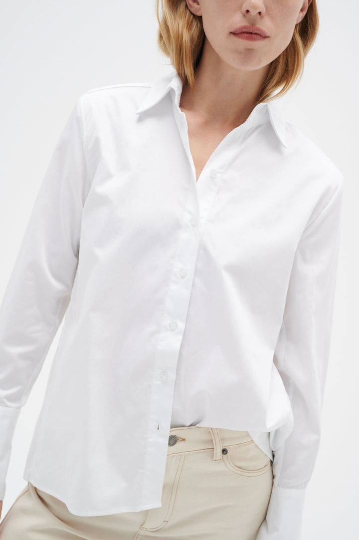 Chemise blanche classique en coton à manches longues avec col traditionnel et boutons visibles.