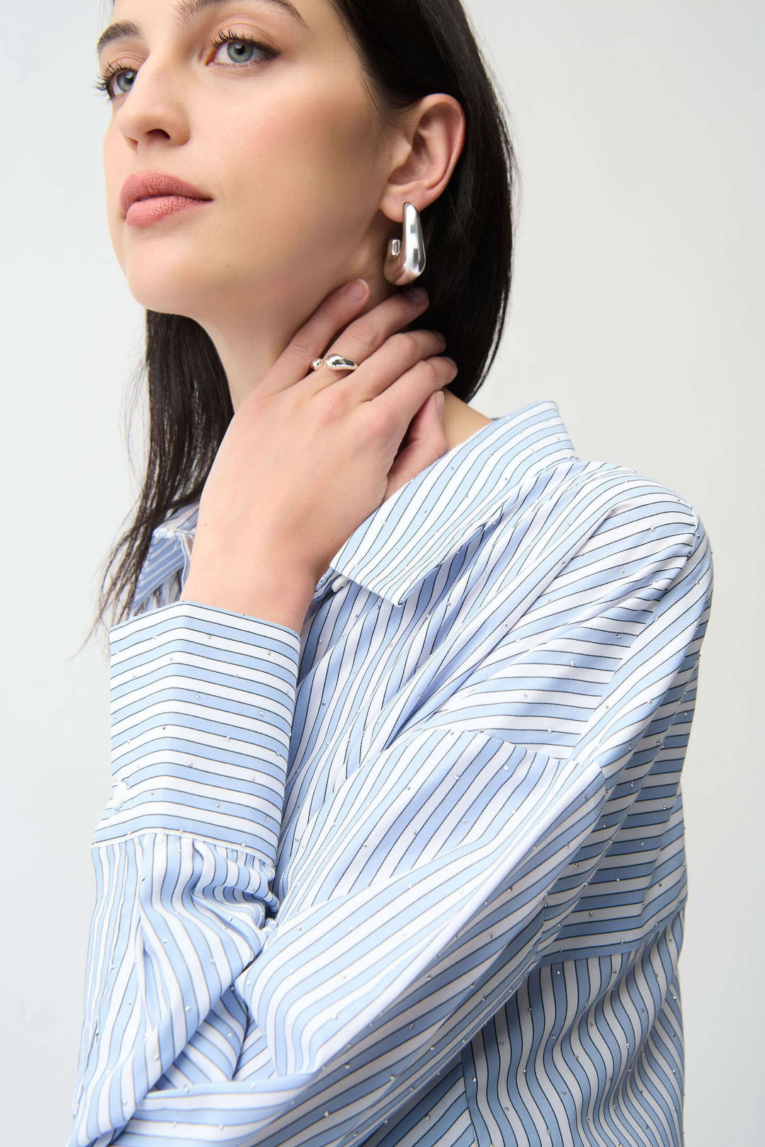 Modèle portant une chemise avec paillettes et rayures verticales, manches longues, col classique, idéale pour un look contemporain.