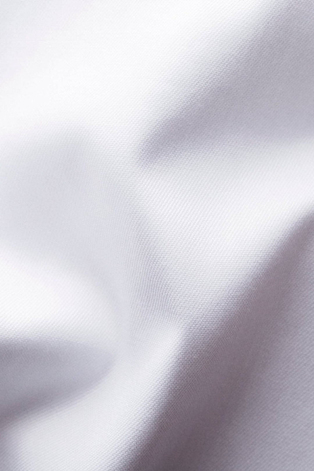 Gros plan sur un tissu blanc infroissable, doux et élégant, idéal pour une chemise de qualité.