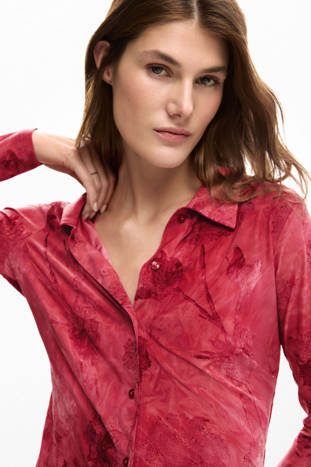 Femme portant une chemise brodée avec fleurs, à manches longues, coupe ajustée, motif artistique élégant et féminin.