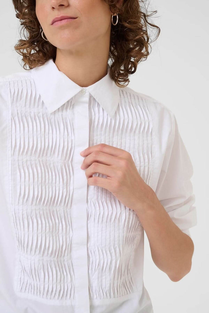 Chemise classique avec plis nervurés blanche, coupe droite, col chemise, détails élégants pour un look sophistiqué et polyvalent.