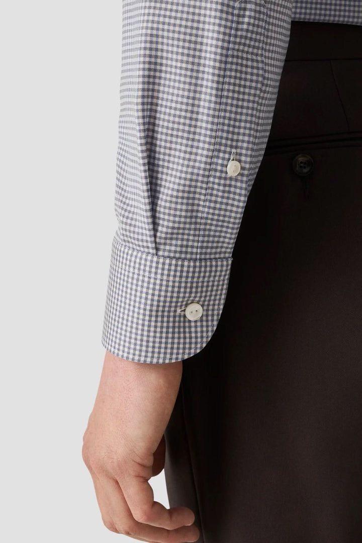 Détail du poignet d'une chemise en laine mérinos à micro-carreaux avec boutons en nacre.