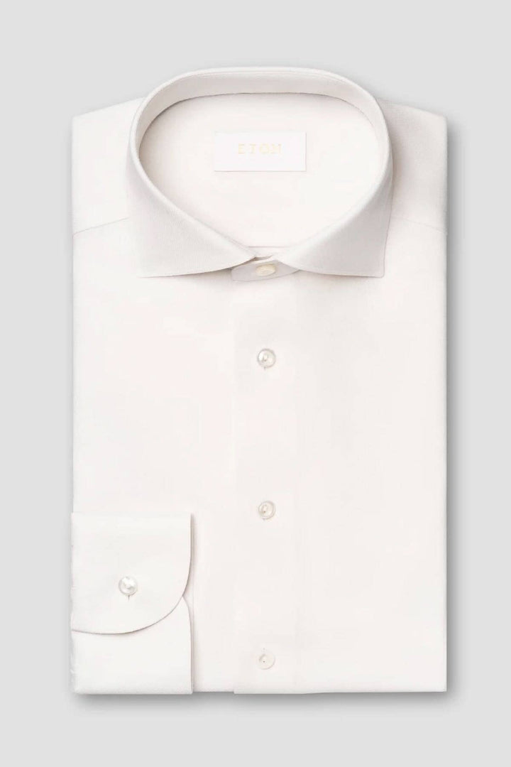 Chemise blanche en laine mérinos, col doux et boutons en nacre, élégante et confortable.