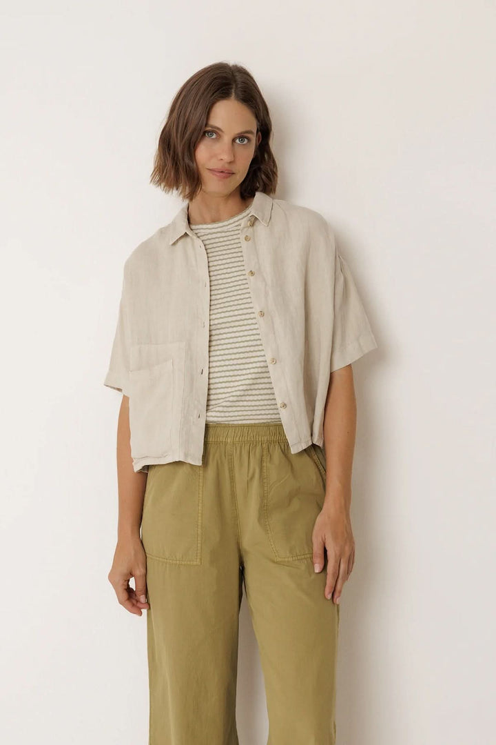 Femme portant une chemise en lin à coupe décontractée, col classique et poche plaquée, offrant un style élégant et fluide.