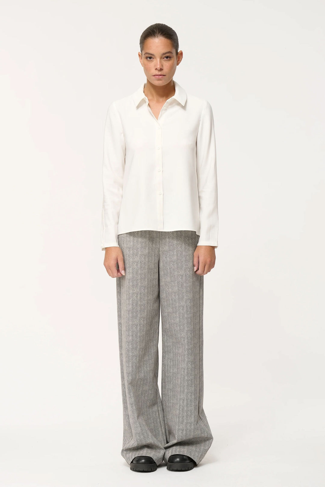 Chemise fluide élégante et confortable avec coupe ample, col classique et fermeture boutonnée, portée avec un pantalon large.