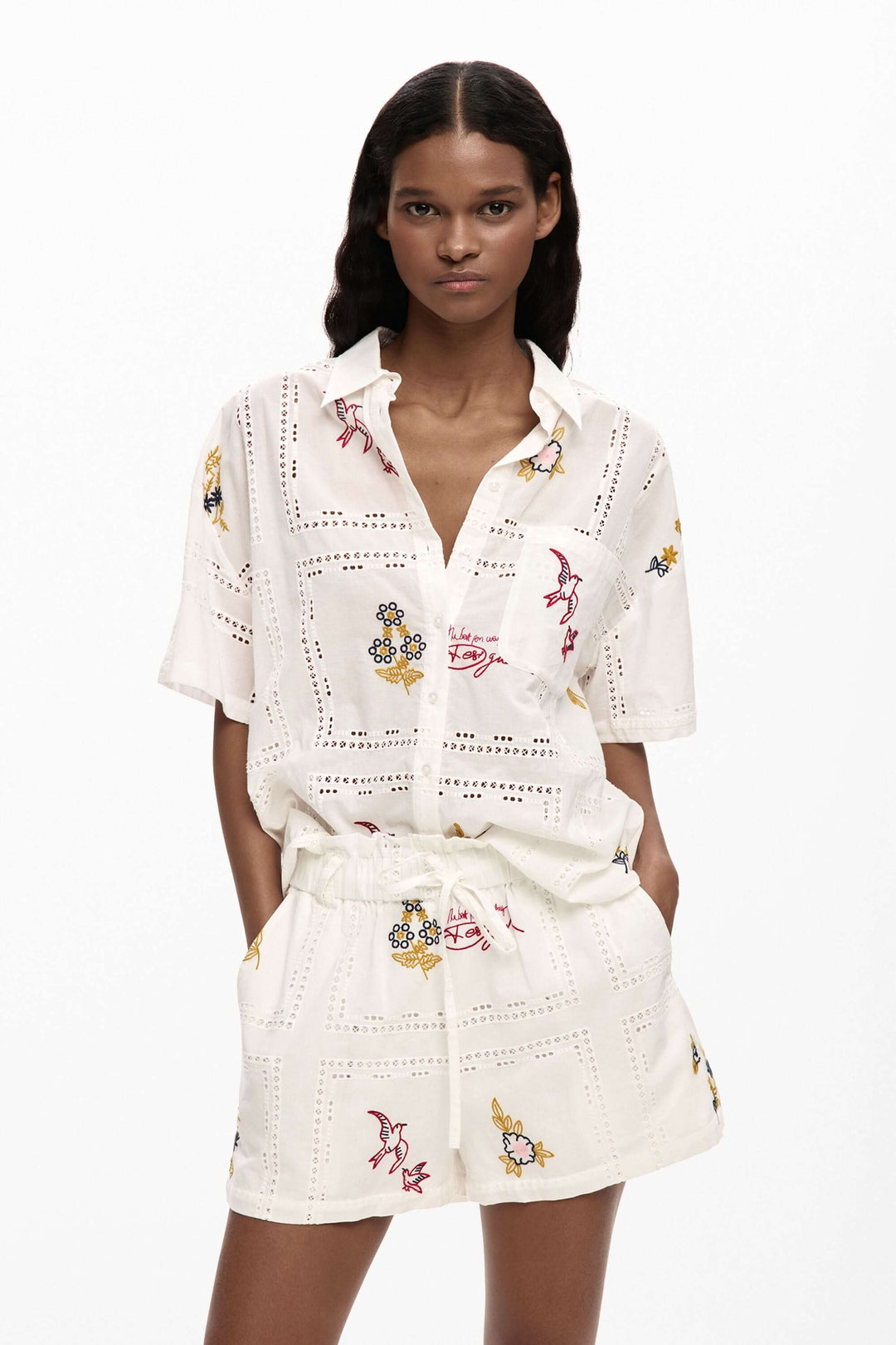 Chemise fluide brodée à manches courtes avec broderies délicates et coupe structurée, idéale pour un look féminin et élégant.