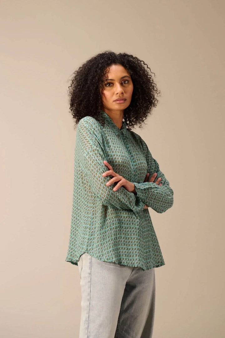 Femme portant une chemise fluide imprimé avec motif géométrique, col classique, manches longues, coupe décontractée.