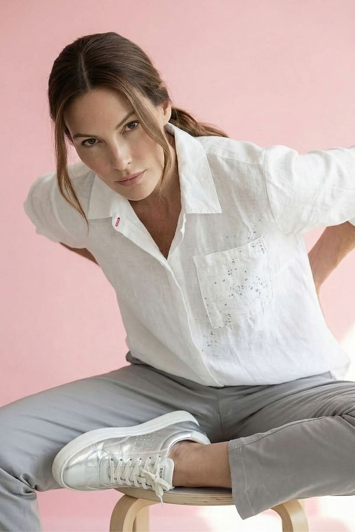 Chemise imprimée à manches retroussables portée par une femme avec fond rose, style décontracté et élégant.