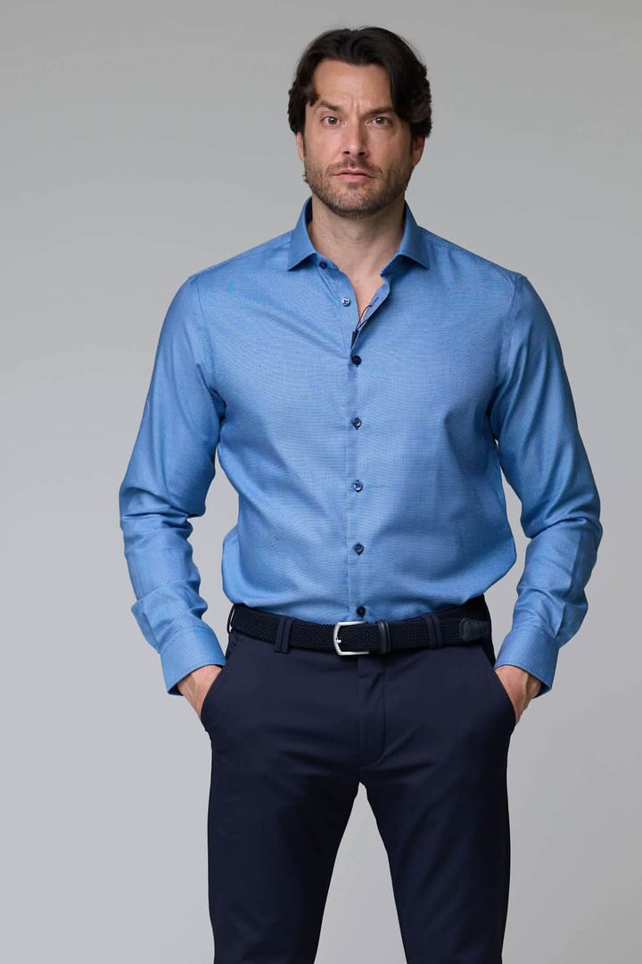 Homme portant une chemise à micro-motif texturé bleue, manches longues, coupe ajustée, idéale pour bureau ou occasion chic.