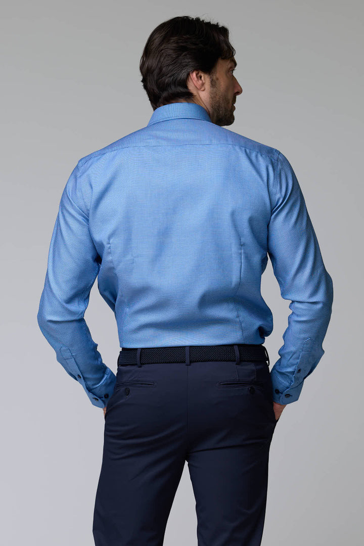 Homme portant une chemise à micro-motif texturé bleu, idéale pour le bureau ou une occasion chic, vue de dos.