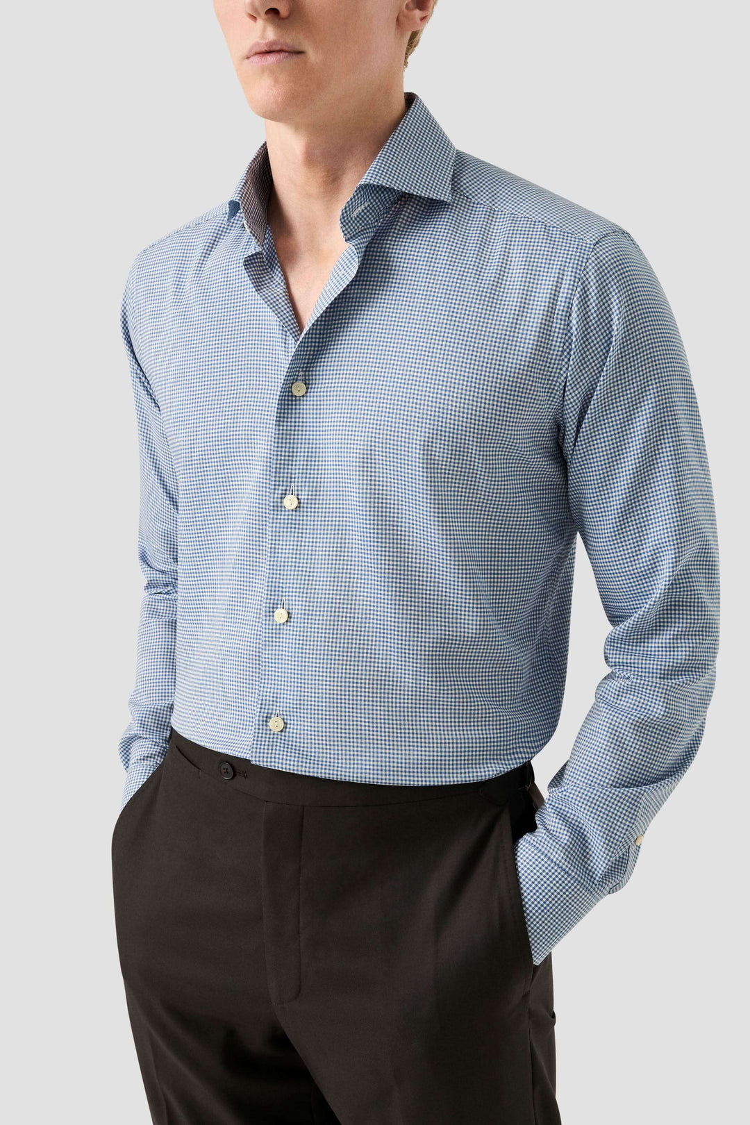 Homme portant une chemise motif carreaux à col classique ouvert et coupe ajustée, un style moderne et élégant.
