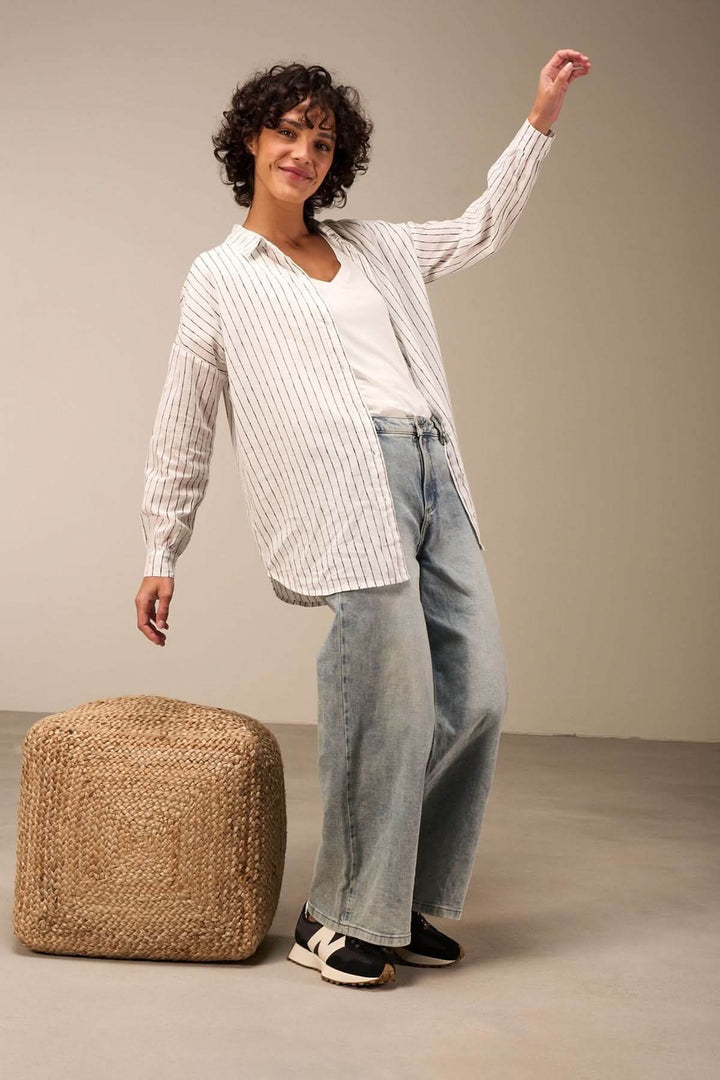 Femme portant une chemise oversize à rayures verticales avec un look casual chic et un pantalon large.