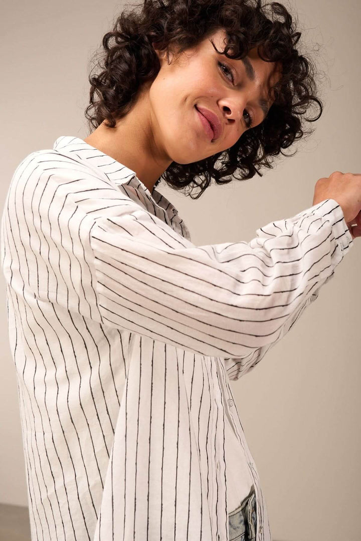 Modèle portant une chemise oversize à rayures verticales, alliant élégance et décontraction.