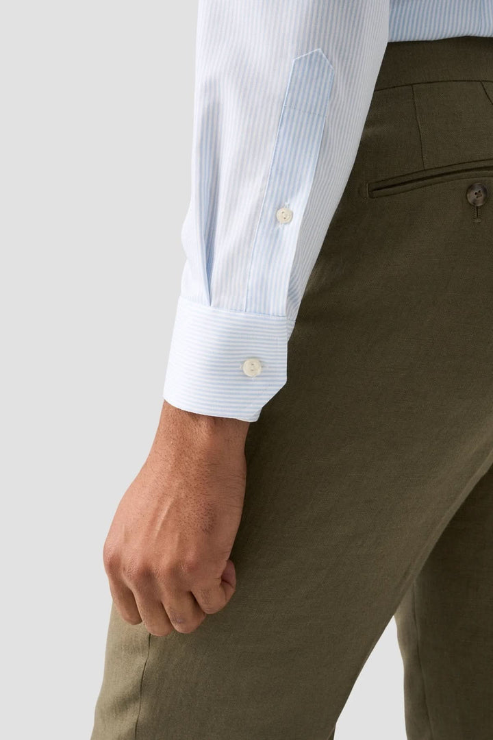 Chemise rayée en coton et lyocell avec manches à fines rayures bleues, portée avec un pantalon élégant pour un look moderne.