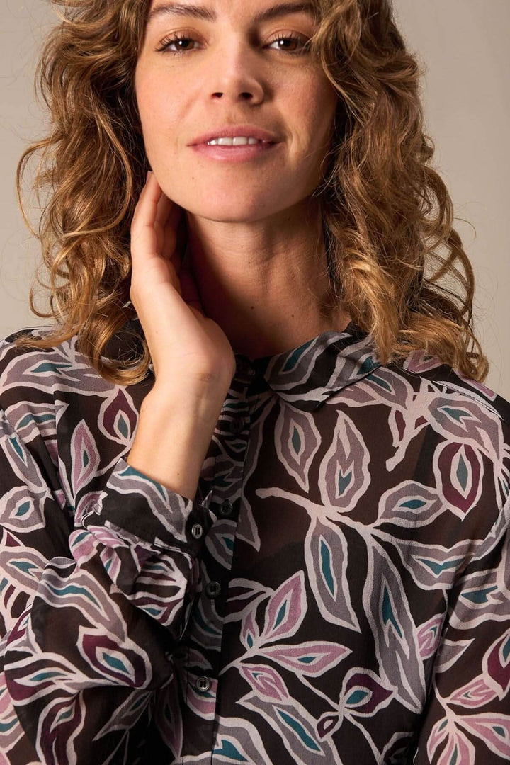 Femme portant une chemise semi transparente en chiffon avec imprimé allover floral, montrant un look élégant et raffiné.