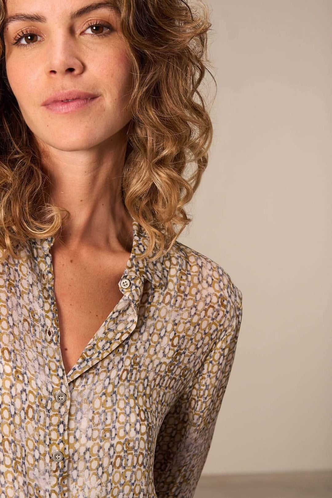 Femme portant une chemise semi-transparente à motifs, manches longues, style élégante et décontracté.