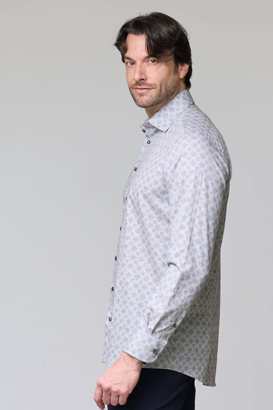 Homme portant une chemise sport à motif géométrique bleu pâle avec col classique, boutons bleus nacrés, vue de profil.