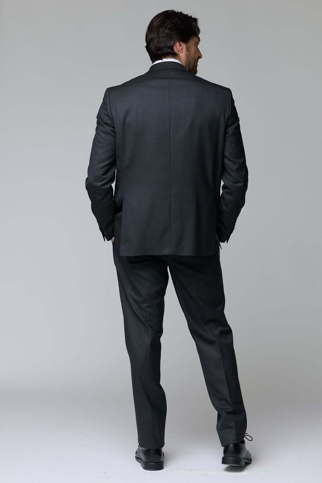Homme portant un complet classique deux pièces en tissu structuré, vue de dos, accent sur l'élégance intemporelle et le confort optimal.