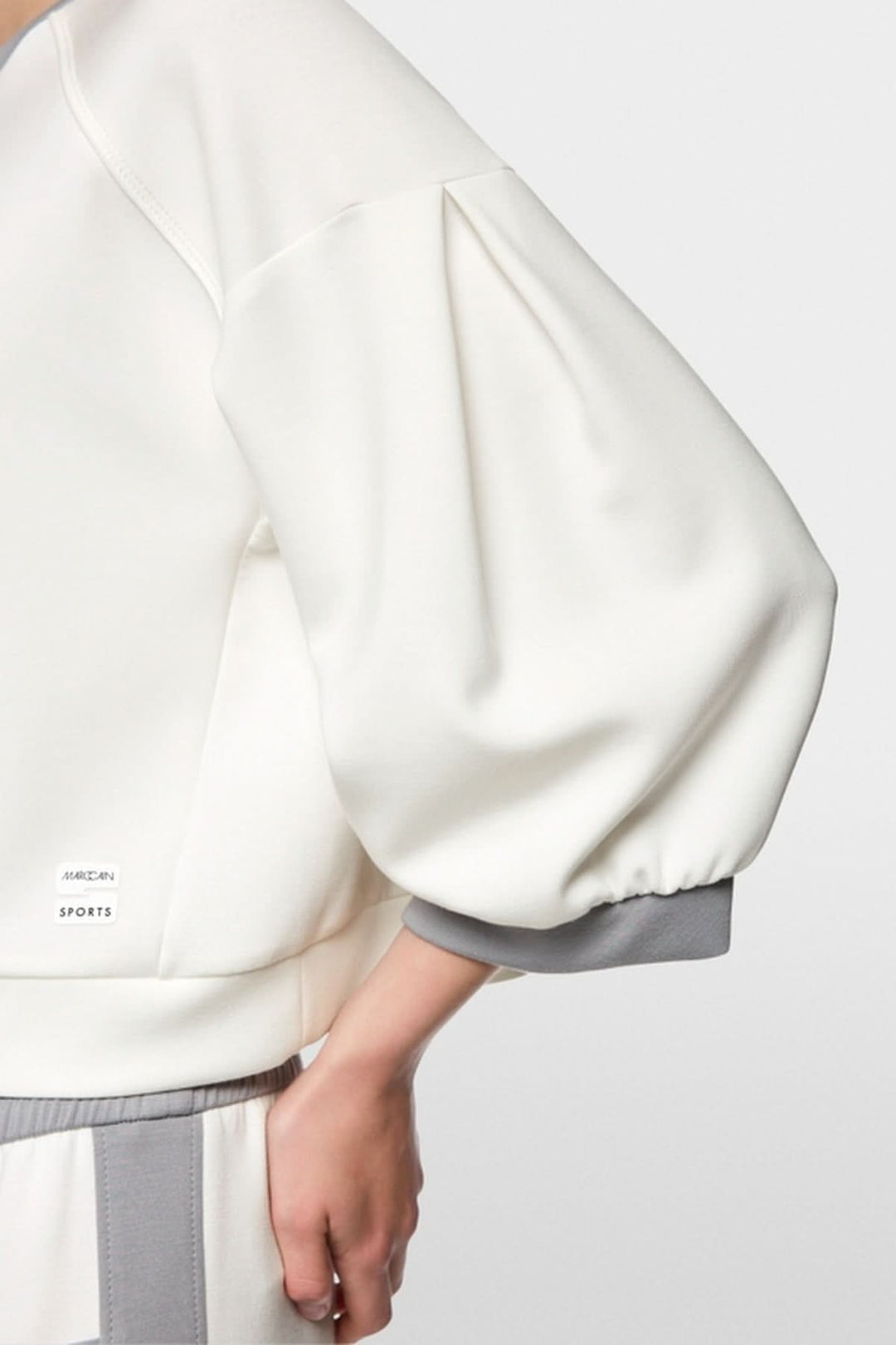 Coton ouaté décontracté avec manches bouffantes et coutures contrastées, logo Marc Cain Sports visible sur le bas.