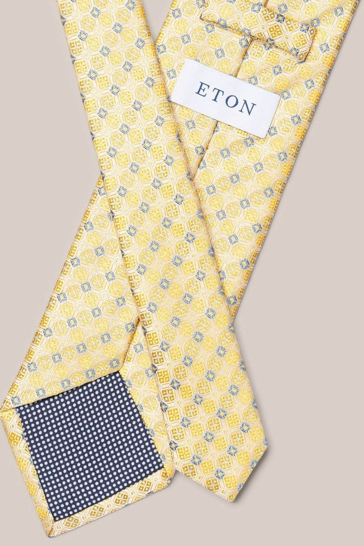 Cravate de soie jaune avec motifs géométriques et finitions élégantes, parfaite pour un look formel.