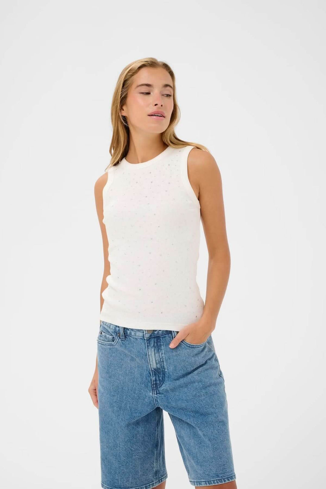 Débardeur sans manches blanc avec strass, coupe ajustée et encolure ronde, porté par une femme avec un jean pour un look casual chic.