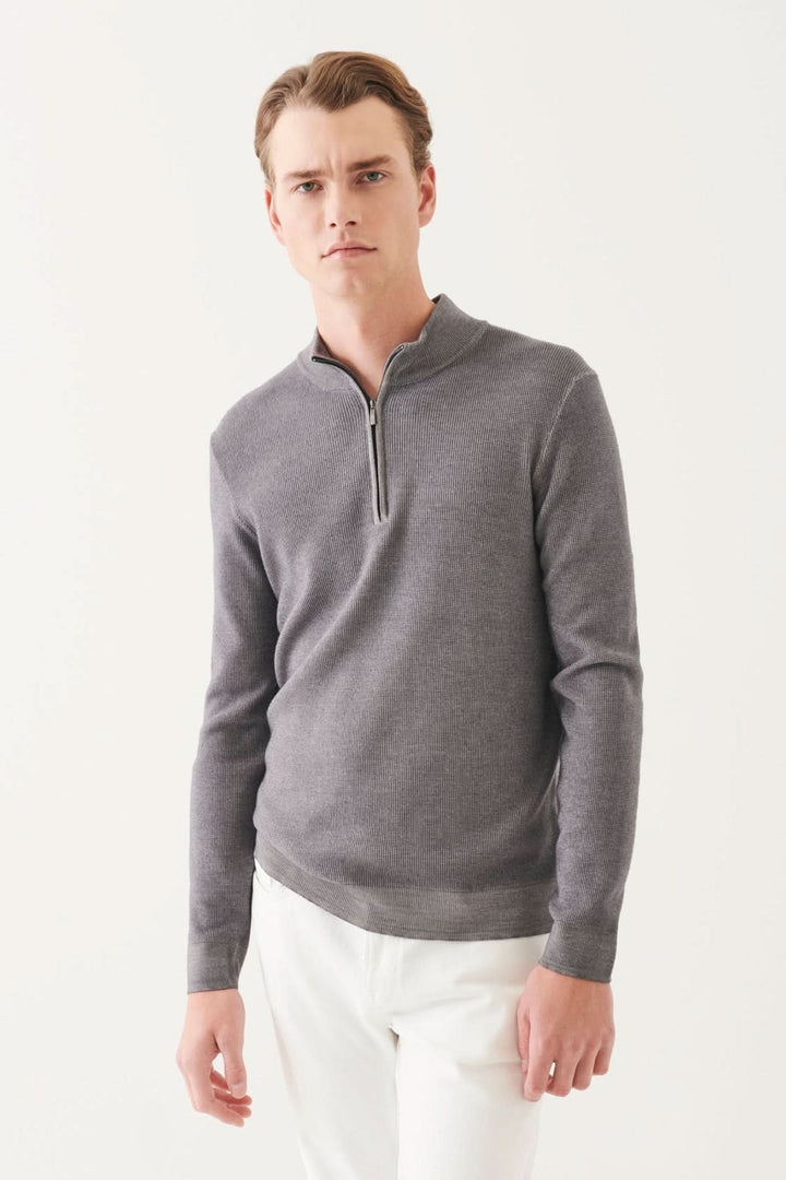 Homme portant un demi-zip texturé en mérinos extra-fin, couleur gris, avec pantalon blanc.