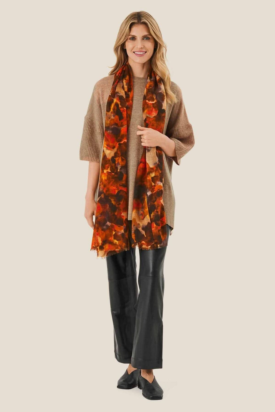 Foulard Adama aux couleurs brûlées, porté avec un pull beige et un pantalon noir, pour un look décontracté.