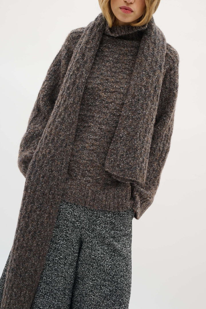 Modèle portant le Foulard Graia en maille texturée avec un manteau, idéal pour la saison froide, ajoutant confort et élégance à la tenue.