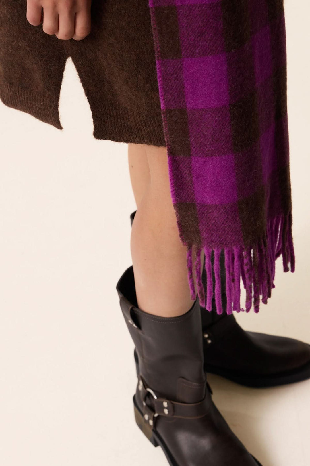 Foulard à carreaux violet et marron porté avec une tenue élégante, ajoutant chaleur et style.