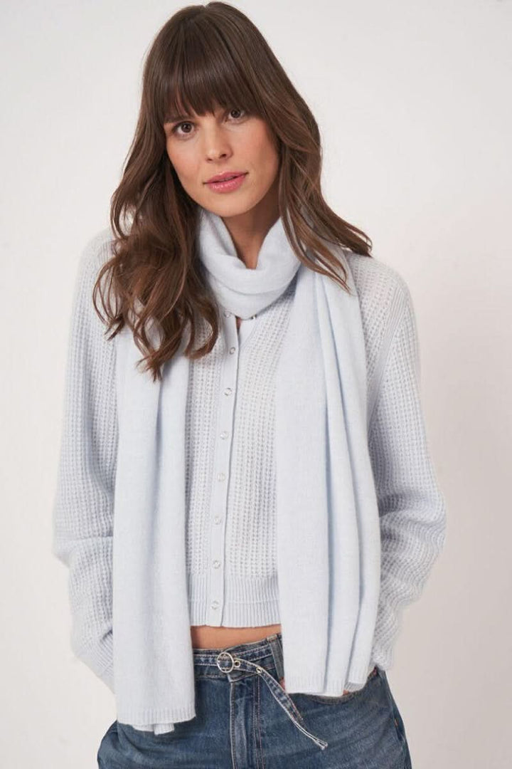 Femme portant un foulard doux essentiel en textile léger, drapé autour du cou, ajoutant une touche élégante à sa tenue simple.