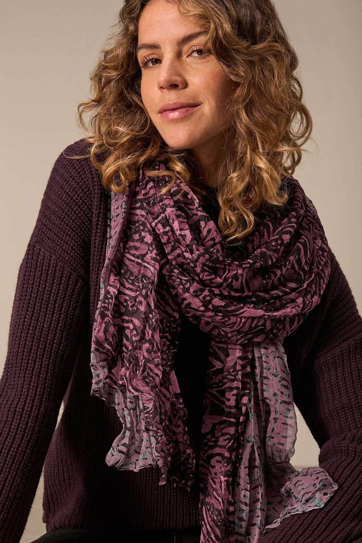 Foulard paréo en soie avec imprimé intégral, porté par une femme aux cheveux bouclés, ajoutant une touche d&