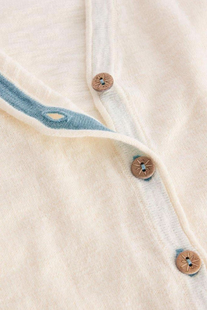 Gilet col V Naria blanc cassé avec boutons marron et bordure bleue, élégant et décontracté.
